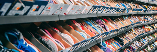 Rows of boxed trainers filling a retail stockroom wall