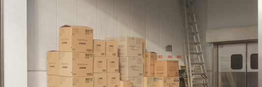Cardboard cartons from a bulk delivery stacked on a warehouse floor