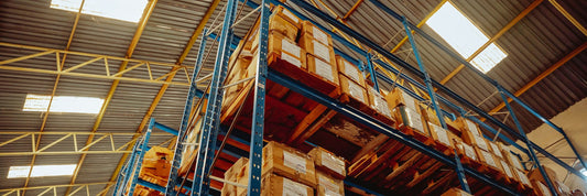 A tall stack of unopened cartons filling a warehouse aisle