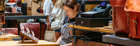 Shoppers browsing bags on display in an independent leather goods shop