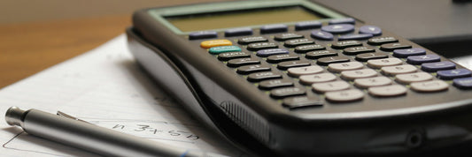 Calculator and pen resting on a printed costing sheet