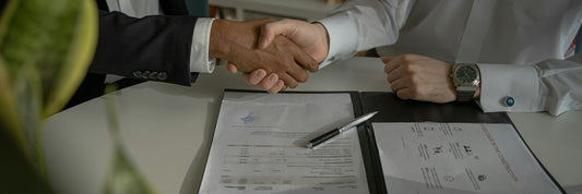 Two people shaking hands over a signed order document