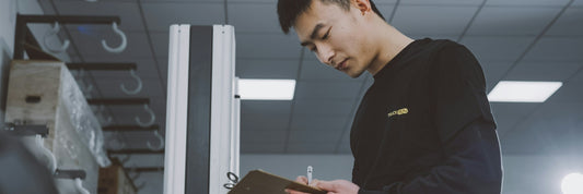 Inspector with a clipboard checking stock on a factory floor