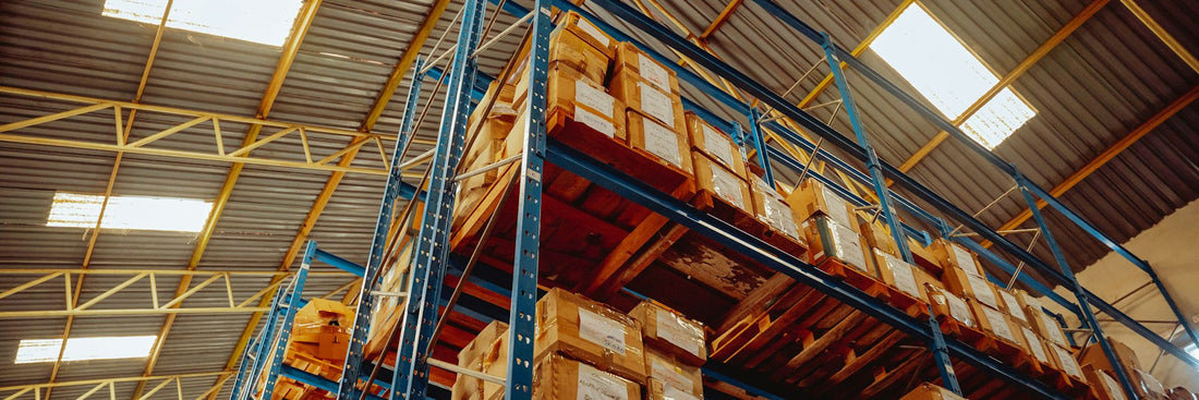 A tall stack of unopened cartons filling a warehouse aisle